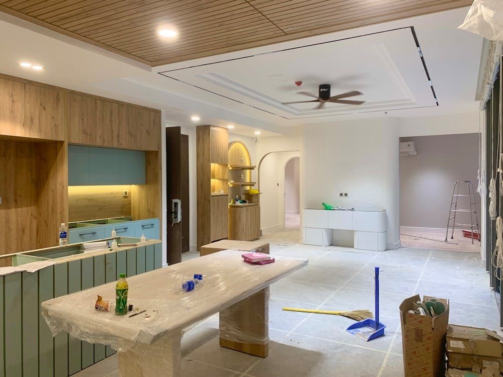 Modern kitchen under renovation with wooden cabinets, painted walls, and a ceiling fan.